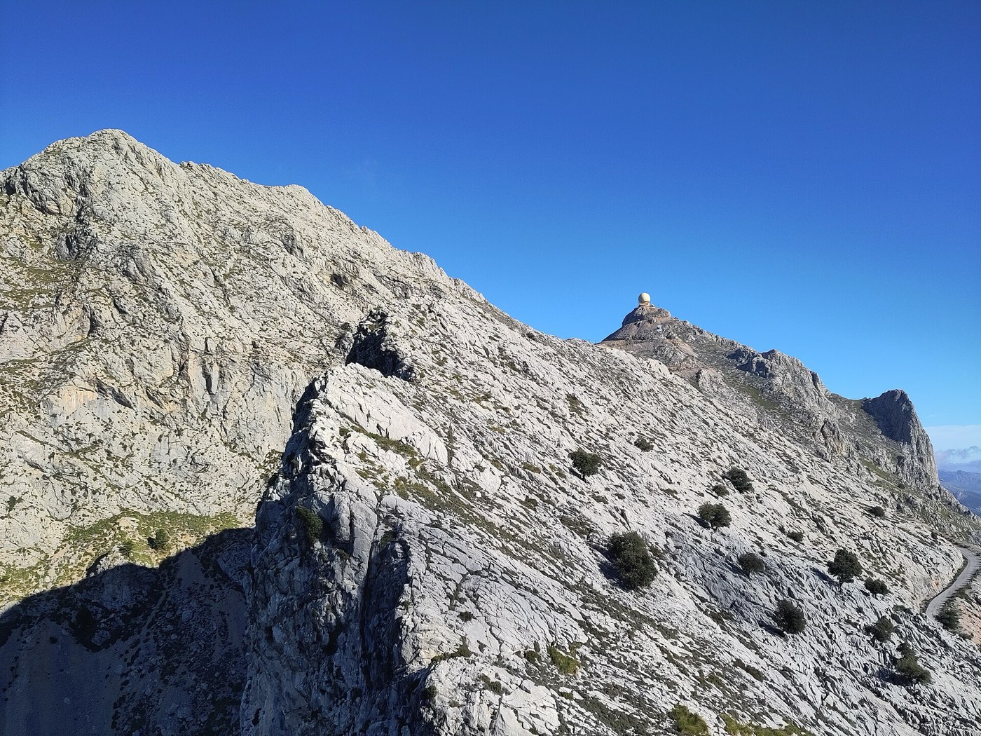 La cúpula de radar del Puig Major traient el cap just per sobre d'una carena rocosa de la Serra de Son Torrella en primer terme