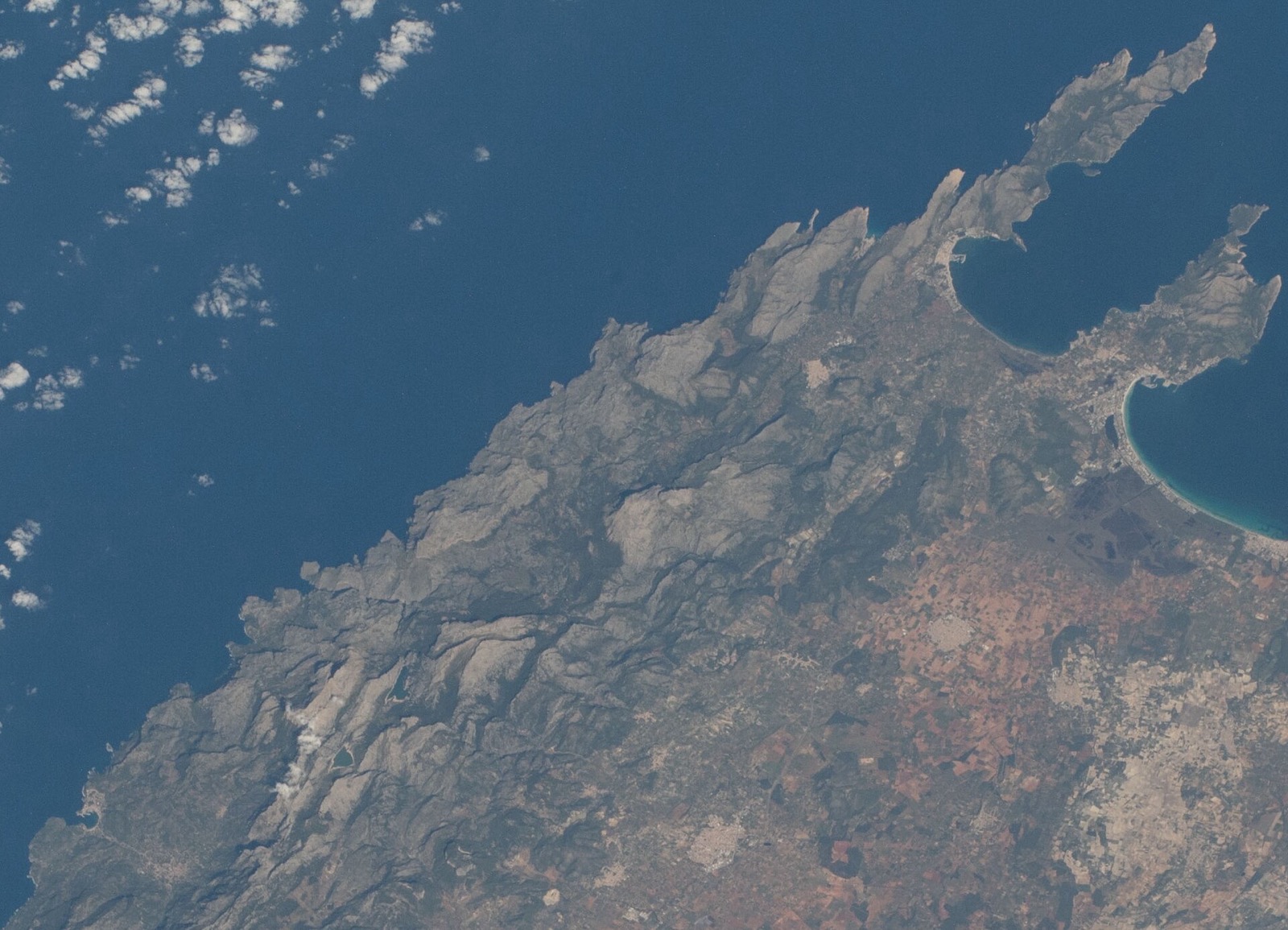 La costa nord-oest de Mallorca des de l'Estació Espacial Internacional: la Serra de Tramuntana com una muralla contínua de roca grisa al llarg de la costa, amb la península de Formentor a dalt a la dreta i l'interior pla de l'illa al darrere