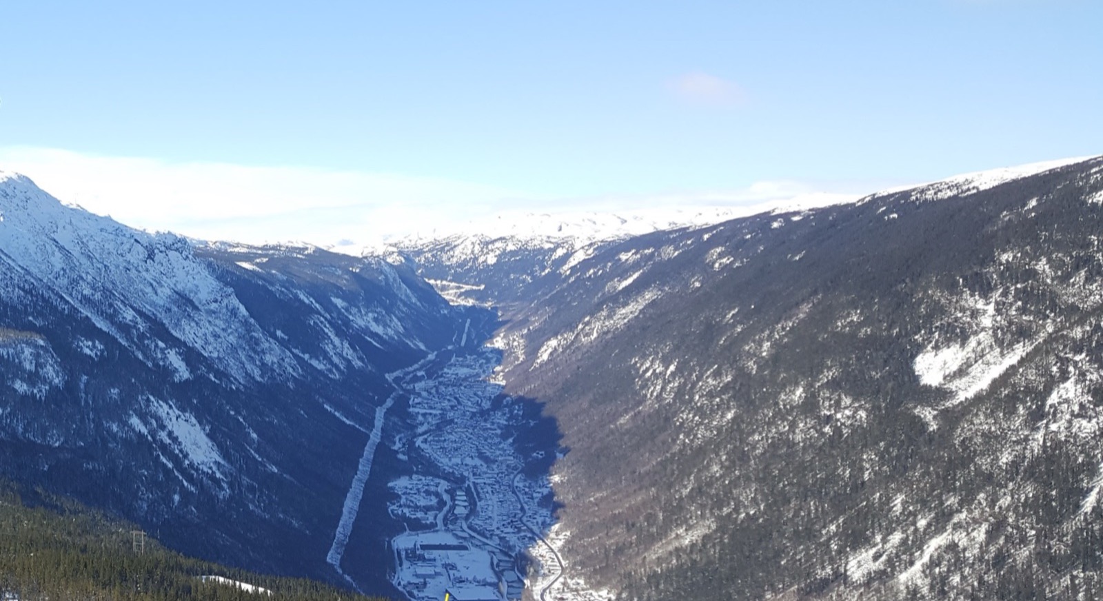 Rjukan alineado en el fondo del Vestfjorddalen en marzo: todo el pueblo en la sombra de la montaña a mediodía mientras las crestas de arriba están a pleno sol